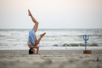 a woman doing a yoga pose on the beach