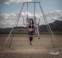 a woman is sitting on a swing in the desert